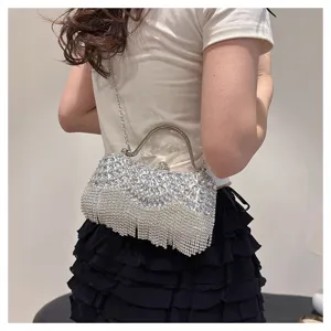 Macro view of a shimmering rhinestone evening clutch bag with delicate silver tassels.