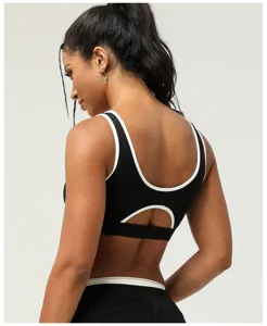 Vue arrière détaillée d'un soutien-gorge de sport noir avec bordure blanche et dos ajouré.