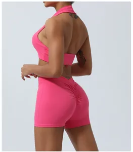 Pink two-piece yoga set with halter crop top and scrunch butt fitness shorts for women.