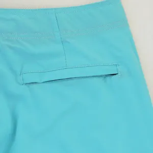 Vista dettagliata di pantaloncini da bagno turchese da uomo con cintura elastica e tasca posteriore.