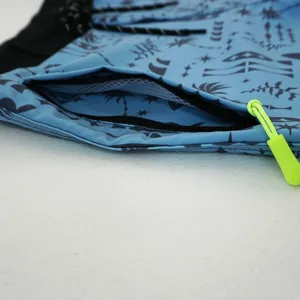 Dettaglio della tasca dei pantaloncini da bagno, tessuto blu con tirante verde neon.