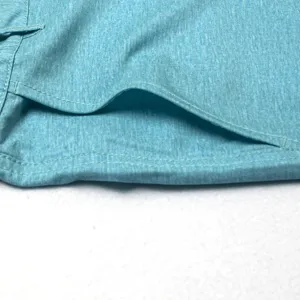 Gros plan détaillé du tissu extensible turquoise à séchage rapide avec coutures.