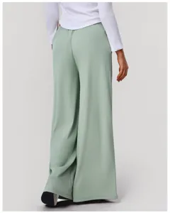 Back view of high-waisted draped wide leg pants in light green, smooth flowy fabric detail.