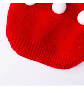 Gros plan détaillé du pull tricoté pour animaux rouge avec pompons blancs et bord côtelé.