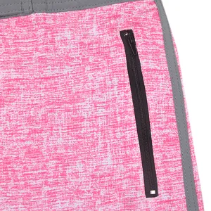 Close-up detail of men's board shorts, pink textured fabric with black zipper pocket.