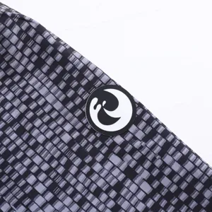 Vue détail de short de bain homme avec motif quadrillé noir et badge logo de marque.