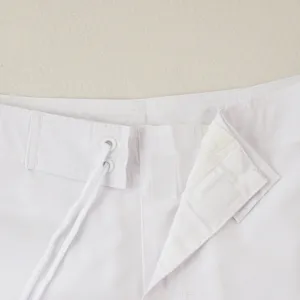 Primo piano sui dettagli della vita dei pantaloncini da surf bianchi da uomo con coulisse.