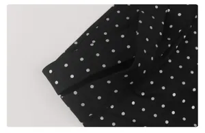 Close-up van zwarte stip yoga broek hoge taille kruis detail, elastische stofkwaliteit.
