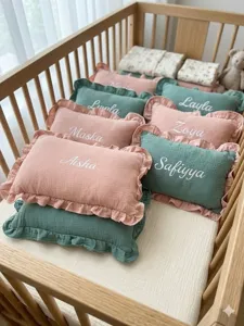 Detail view of cotton muslin baby ruffle pillow, soft pink and green decorative cushion.