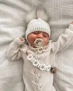Handmade daisy baby pacifier clip with cute knit outfit detail for soothing infants daily use