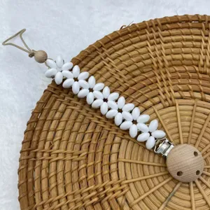 Detailed close-up view of a handmade white flower beaded pacifier clip with natural wooden beads.