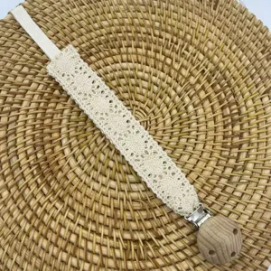 Vue rapprochée de l'attache-tétine en dentelle beige avec perle en hêtre et clip.