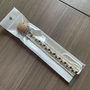 Detailaufnahme der blumenbestickten Schnullerkette im Vintage-Stil mit Holzclip.