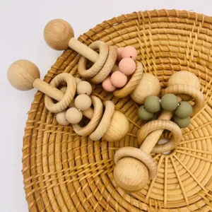 Detailansicht handgefertigter Holz Silikon Baby Rasseln mit sicheren Beissperlen auf Rattanteller.