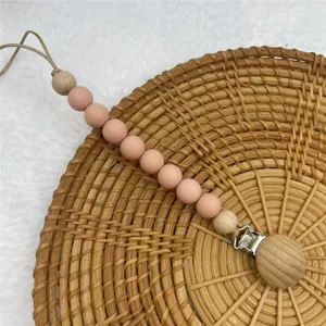 Silicone pacifier clip detail shot, featuring pink beads and wooden parts for baby teething.