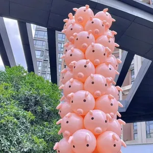 Detailed shot of giant pink pig shaped inflatable balloons stacked as party decoration column.