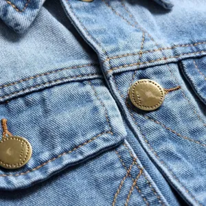 Denim jacket detail close-up, classic blue fabric texture with contrast stitching buttons.