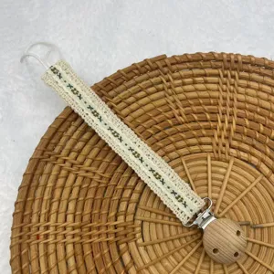 Nahaufnahme des vintage-pastoralen blumig bestickten spitzen Schnullerclips mit Holzkugel.