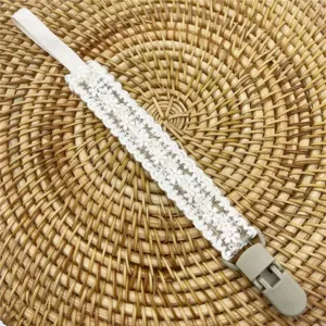 Attache-tétine en dentelle blanche de détail, parfait pour les jouets de dentition bébé.