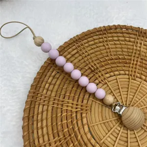 Silicone wooden pacifier clip detail shot, baby teething chain with purple beads and metal clasp.