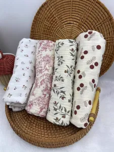 Newborn printed cotton gauze swaddle blanket set, rolled presentation in tray main view.