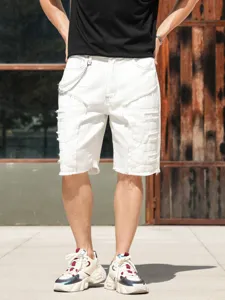 Short en denim blanc pour homme avec écussons déchirés, chaîne et ourlet brut style urbain.