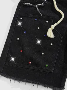 Dettaglio di pantaloncini in denim nero con strass colorati e coulisse con nappine.