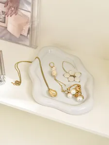 Detail view of cloud-shaped jewelry display tray with gold necklace earrings and ring.