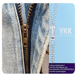 Close-up detail of denim shorts metal zipper and YKK branded tag showing quality hardware.