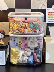 Boîte de rangement de bureau transparente et empilable avec accessoires de cheveux organisés.