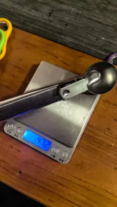Stainless steel ice cream scoop close up view showing exact weight measurement on scale.