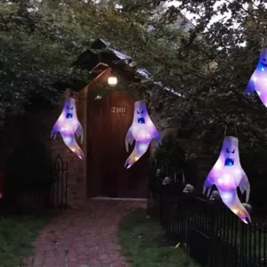 Hängende leuchtende Halloween-Geisterwindsäcke, die einen Baum im Hof schmücken