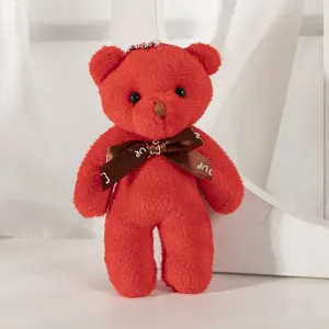 Detailed macro view of a red teddy bear plush keychain featuring a brown silk bow