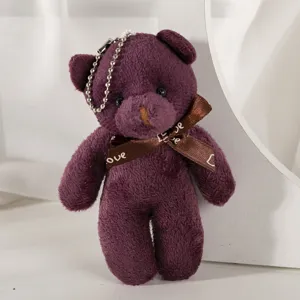 Detailed macro view of a cute purple plush teddy bear keychain with an elegant 'Love' ribbon bow.
