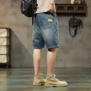 Gros plan détaillé de short en jean bleu délavé pour homme avec coupe décontractée et patch.