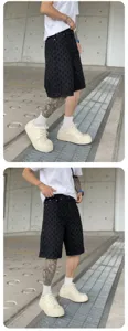 Men's American street style washed black denim shorts, vintage patterned apparel for casual wear.