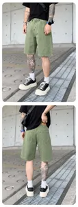 Distressed washed green denim shorts detail view showing relaxed fit and raw texture.
