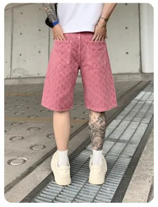 Detailed view of men's pink washed distressed denim shorts, street style casual wear.