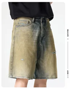 Détail du short en jean déchiré avec délavage vintage, coupe ample droite et longueur genou.