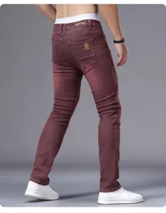 Men's slim fit skinny jeans detail shot, casual burgundy denim trousers with back pockets.