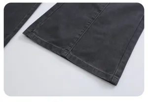 Close-up detail of dark grey washed denim jeans hem, showing fine stitching and fabric texture.