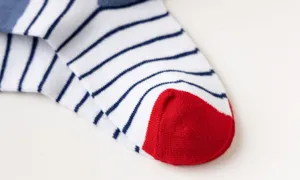 Close-up detail view of children's white and blue striped cotton socks with red toe.