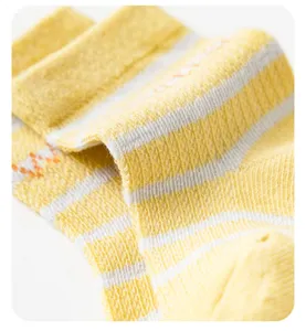 Detailopname van geel-witte gestreepte ademende katoenen babysokken met zachte textuur.