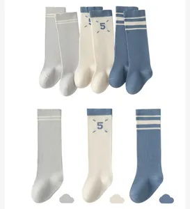 Infant knee-high socks detail view, striped patterns and cute number 5 design, soft cotton.