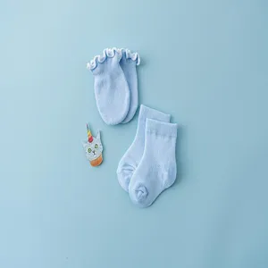 Detail view of light blue baby socks and scratch mittens set, soft cotton infant wear close up.