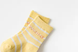 Gros plan détaillé de chaussettes bébé en coton mesh rayées jaune et blanc avec texte.