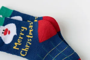Detailed shot of Christmas terry socks with Santa pattern, red heel, and green cuff detail.