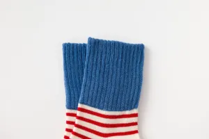 Detail shot of kids cotton socks, blue with red and white stripes, ribbed comfort top.