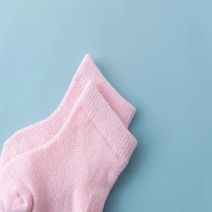 Close-up detail of soft pink knit cotton baby socks showing fine texture against blue background
