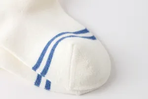 Vista detallada de calcetín de algodón blanco para niños con rayas azules y textura fina.